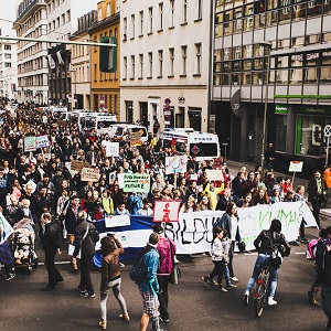 Eine große protestierende Menschenmenge geht durch eine Hauptstraße mit Schildern und Plakaten für Klimaschutz