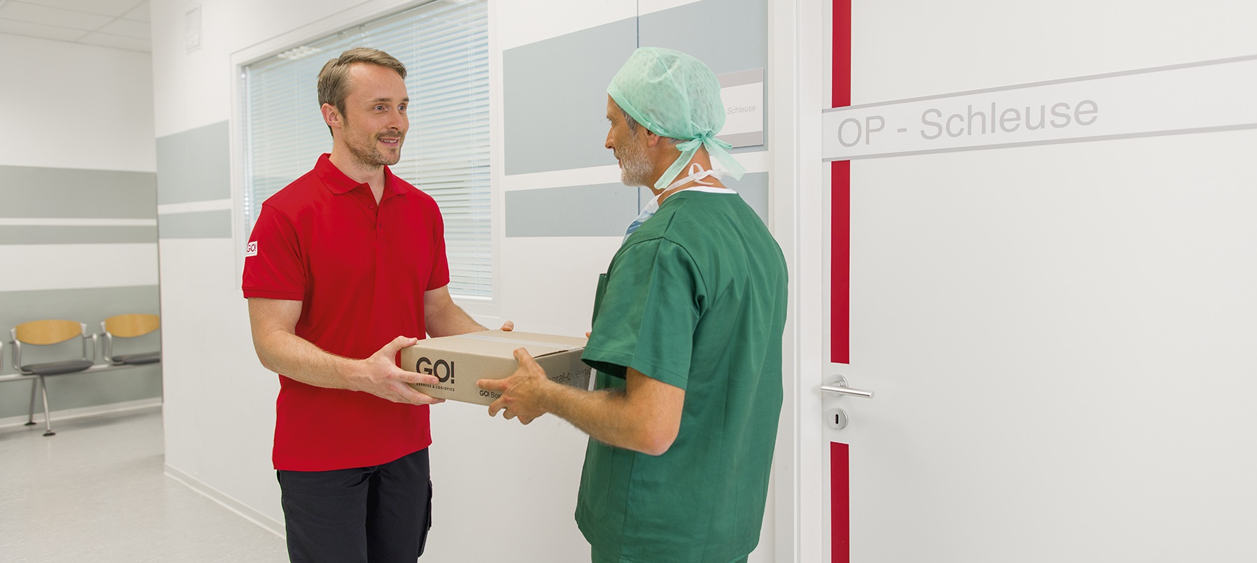 GO! Kurier übergibt Paket an einer OP-Schleuse im Krankenhaus an einen operationstechnischen Assistententen