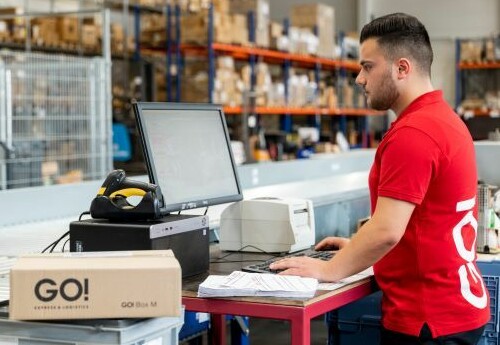 Mitarbeiter in der Tourenbetreuung scannt Paket im Hamburger GO! Express Lager.