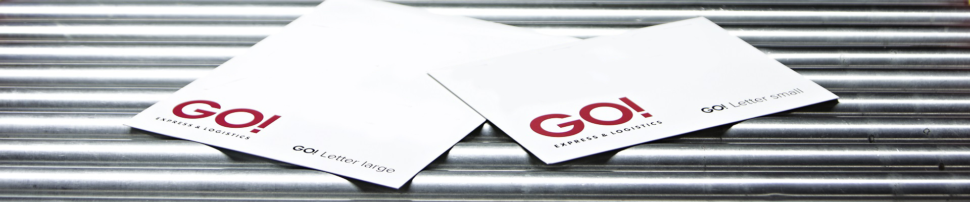 Zwei weiße GO! Letter liegen auf einem metallischen Fließband