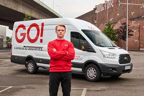 Ein Mitarbeiter steht vor einem GO! Transporter