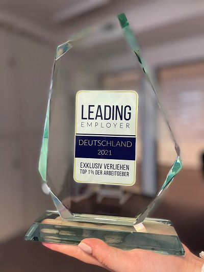 Leading Employer Preis Eine Hand hält den Leading Employer Preis für Deutschland 2021 in die Kamera