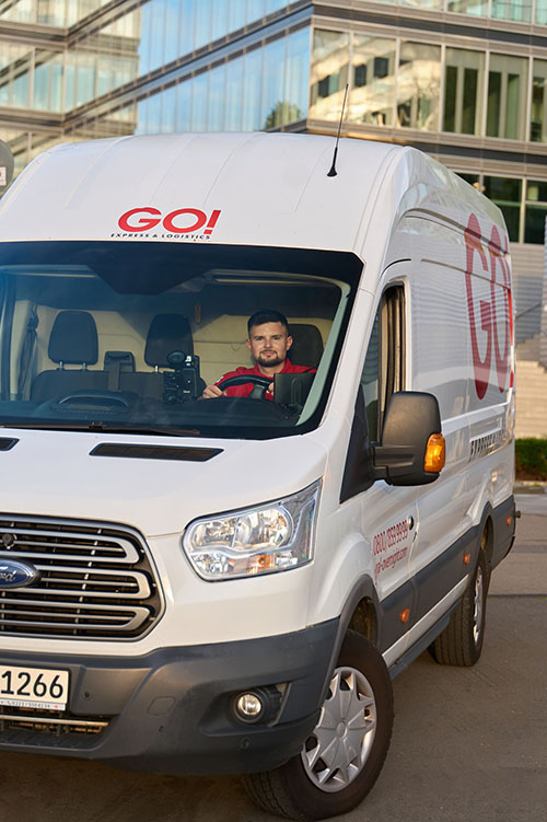 Kurierfahrer (m/w/d) von GO! Express & Logistics sitzt in seinem Transporter. 